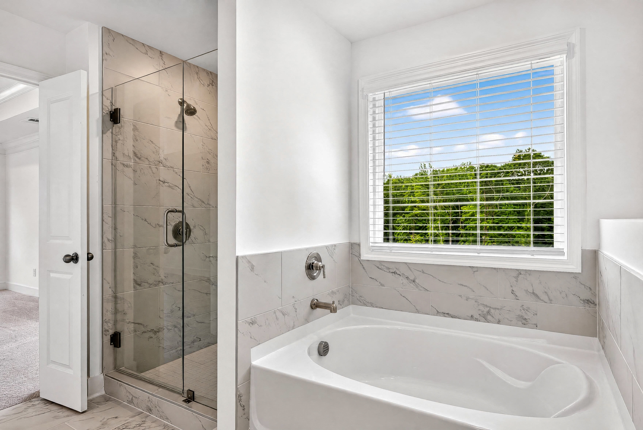 Finished bathroom remodel in New Jersey — frameless glass shower, marble tile, soaking tub with garden view