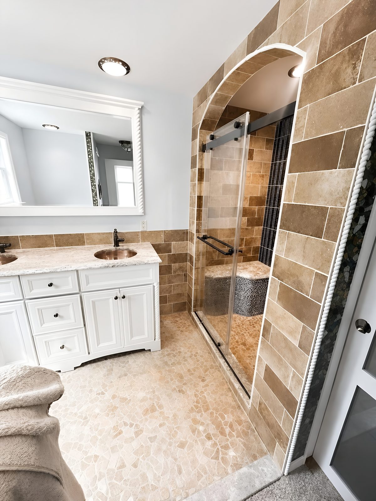 Close-up of the arched, fully tiled shower entry with frameless sliding glass door