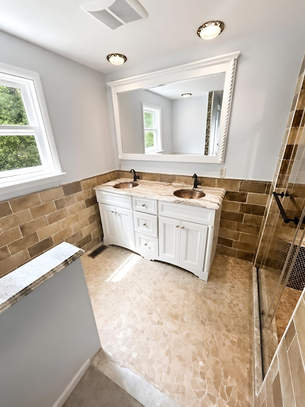 New double vanity with copper vessel sinks, stone countertop, and natural light from a window
