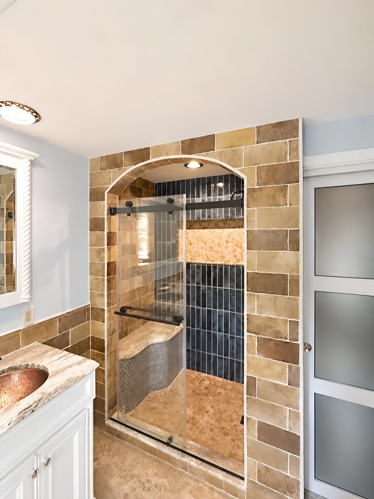 Fully remodeled bathroom in Galloway, NJ by HousePro, featuring an arched tiled shower entry with frameless glass door and a double vanity with copper vessel sinks