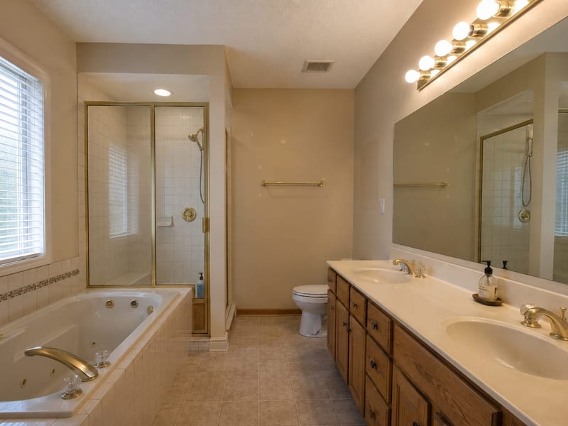 Dated bathroom with builder-grade vanity, tub, and tile, before remodel